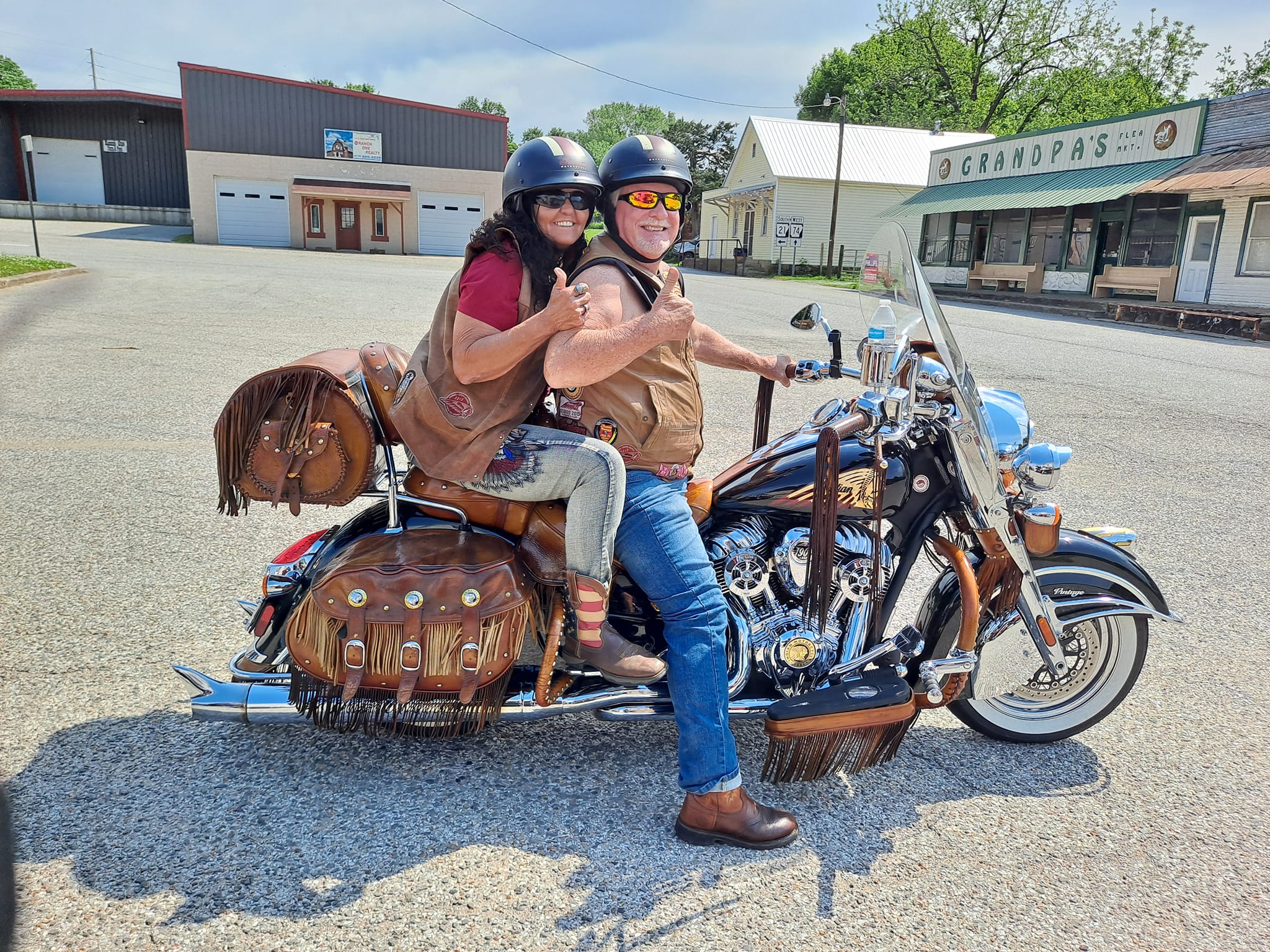 a man and woman riding on the back of a motorcycle