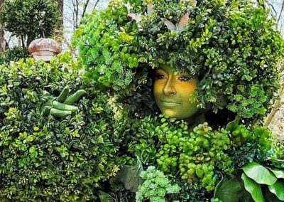 a woman made out of green plants and leaves