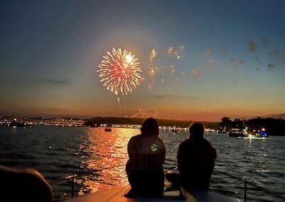 two people sitting on a boat watching fireworks