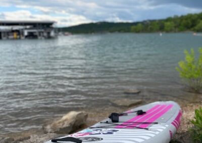 a white and pink kayak sitting on the shore of a lake