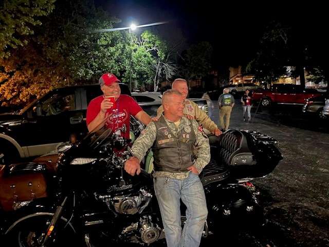 two men standing next to a parked motorcycle