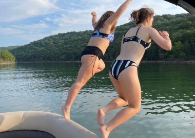two women jumping off the back of a boat