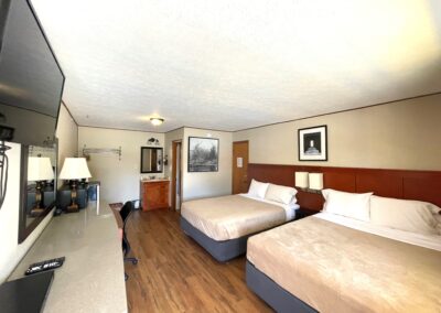 a hotel room with two beds and a flat screen tv