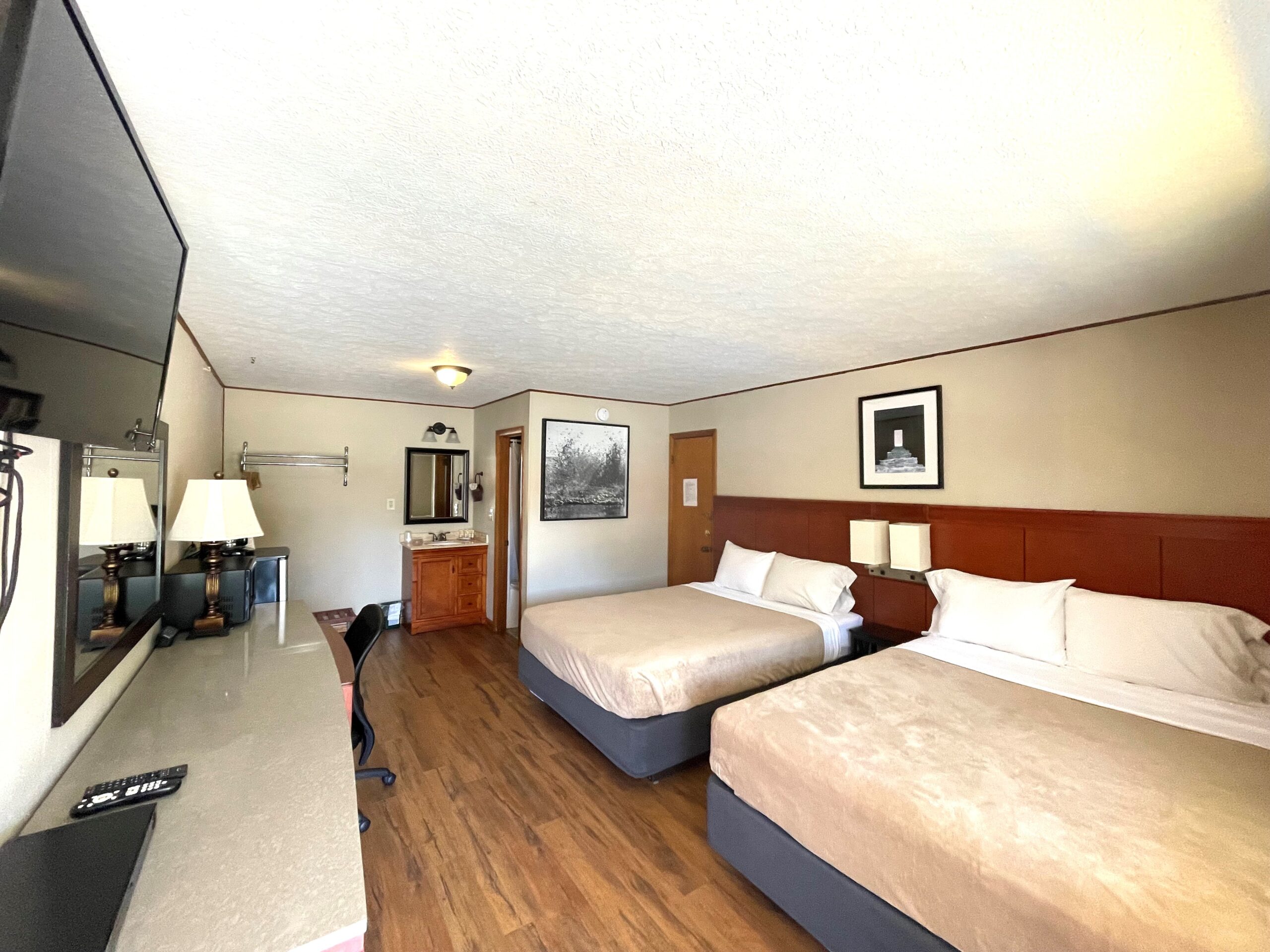 a hotel room with two beds and a flat screen tv