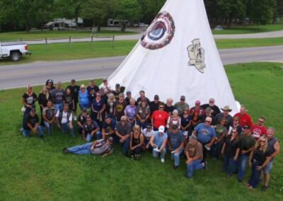 a group of people standing in front of a teepee