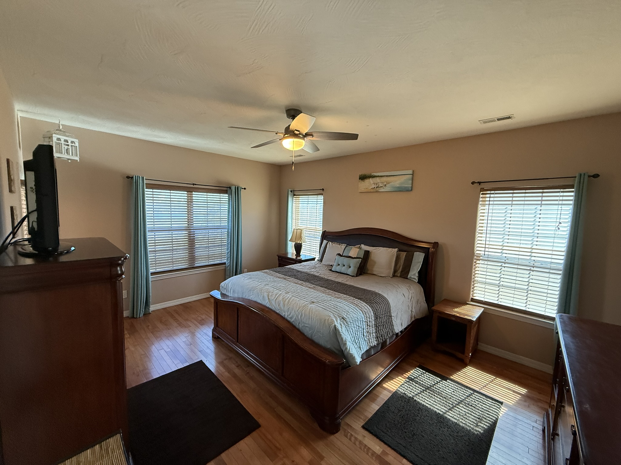 a bedroom with a bed, dresser, and television