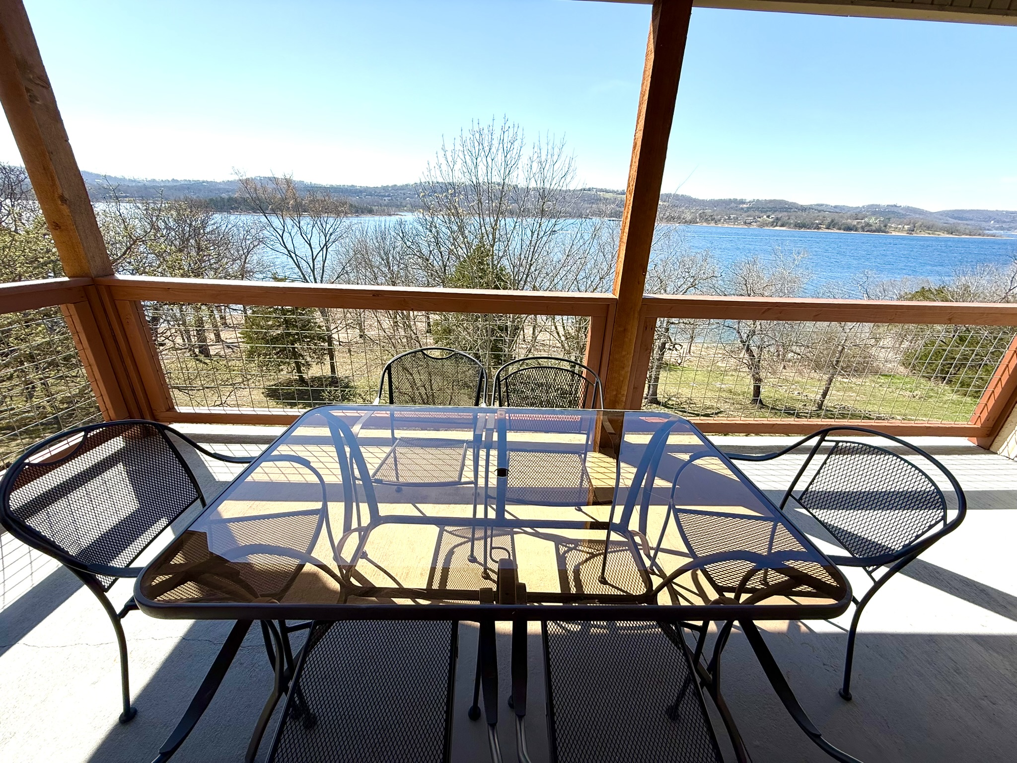 a table and chairs on a porch with a view of a lake