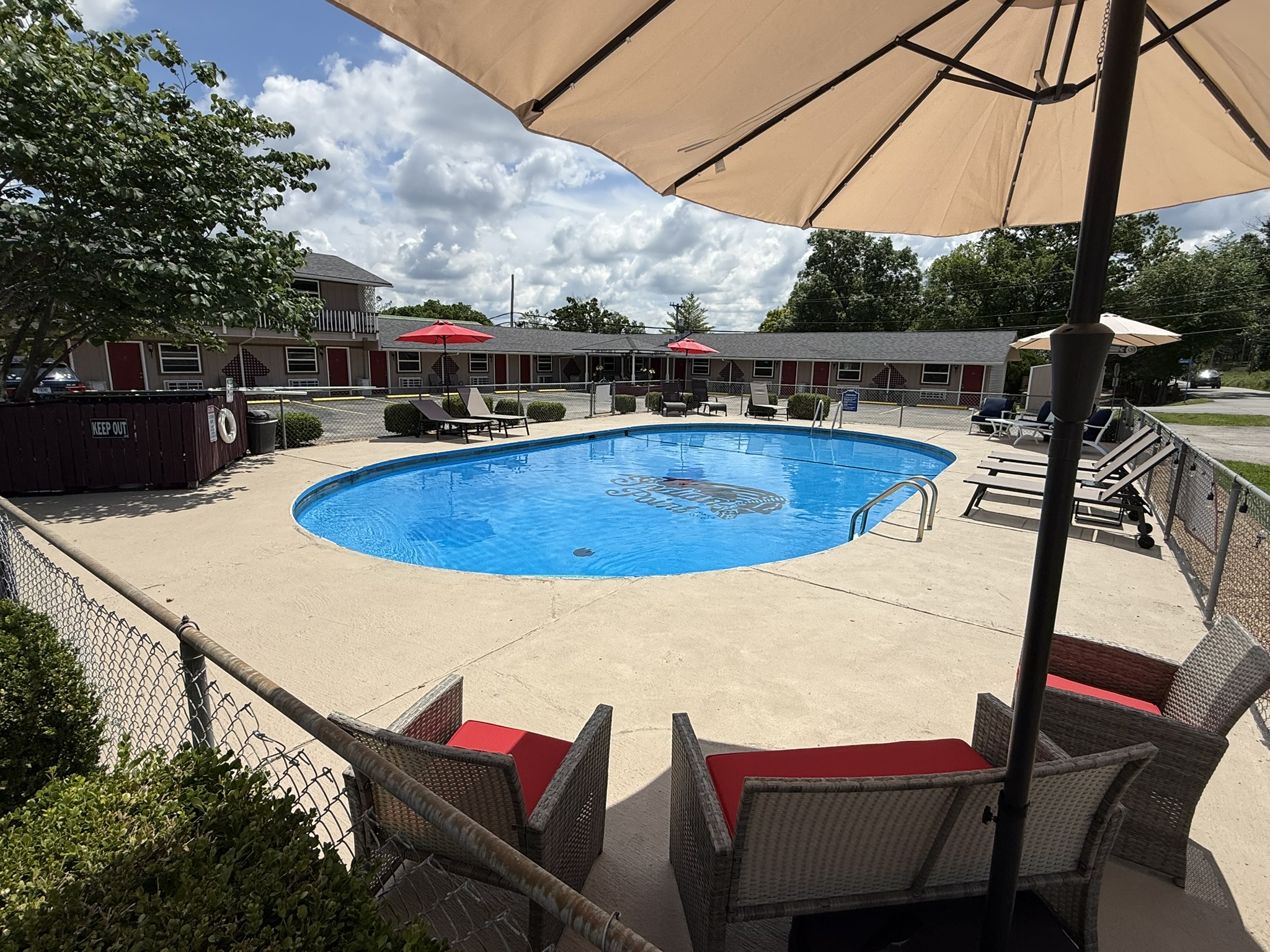 a large swimming pool surrounded by lawn chairs and umbrellas